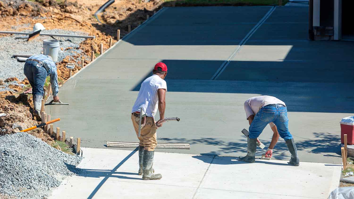 Concrete crew finishing a freshly poured slab for a residential metal building project