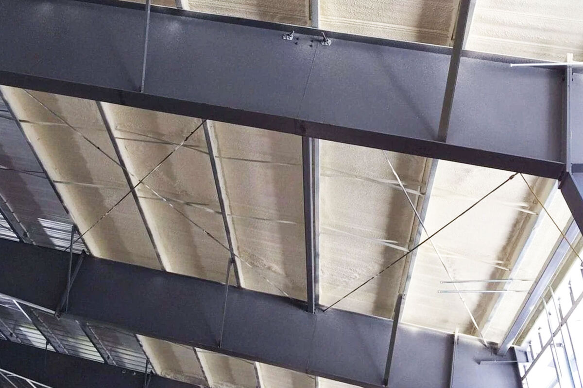 Closed-cell spray foam insulation covering the roof panels and framing inside a metal building
